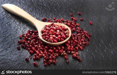 Pink peppercorn with a low-light wooden spoon Placed on a gray background with a rough floor