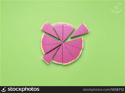 Pink pie sliced in pieces with separated slices on a green background. Pie chart concept. Christmas ruby chocolate tart. Pink chocolate mousse pie.