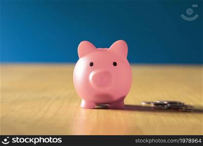 Pink piggy bank on wooden office desk at home with pile of coins, savings,investment business and financial concept close up. Pink piggy bank on wooden office desk at home with pile of coins, savings,investment business and financial concept