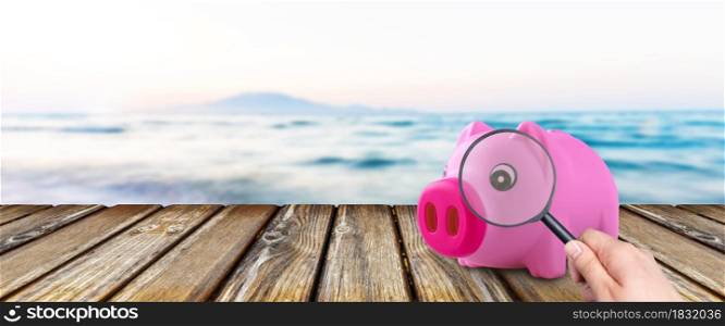 pink piggy bank over background of sea, concept of finding money for a vacation trip
