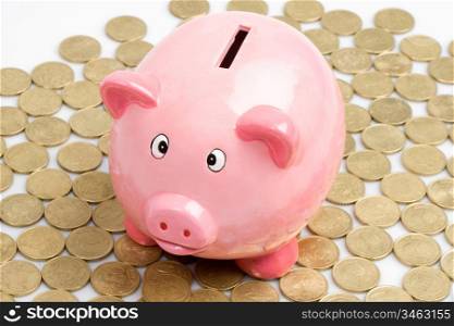 Pink piggy-bank with many currencies outside