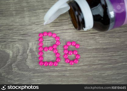 Pink pills forming shape to B6 alphabet on wood background&#xA;