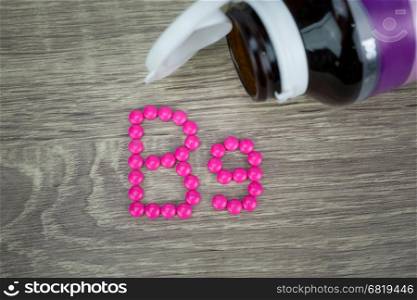 Pink pills forming shape to B9 alphabet on wood background&#xA;