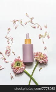 Pink pipette cosmetic bottle with empty label mock up on white background with flowers and petals. Skin care with facial serum. Beauty product template for merchandise. Top view with copy space.