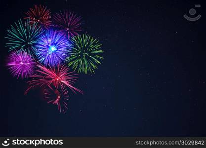 Pink purpe blue green fireworks over night sky. Beautiful pink purpe blue green celebration fireworks located left side over night sky, copy space. Independence Day, 4th of July, New Year holidays salute background.