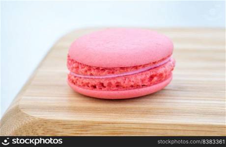 Pink raspberry macaroon on the wooden tray