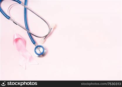 Pink ribbon, symbol of breast cancer awareness with stethoscope, copy space on pink background. Pink ribbon, symbol of breast cancer awareness