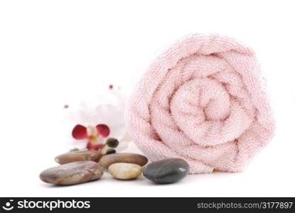 Pink rolled up towel with massage stones on white background
