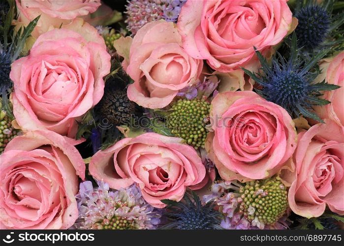Pink roses and blue sea holly in a wedding flower arrangement