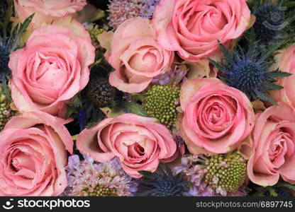 Pink roses and blue sea holly in a wedding flower arrangement