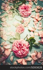 Pink roses composing with flowers petal and leaves on turquoise shabby chic background, top view, retro toned, vertical