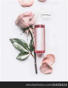Pink Roses essential cosmetic product bottle with branding mock up and rose flowers and petals on white background, top view