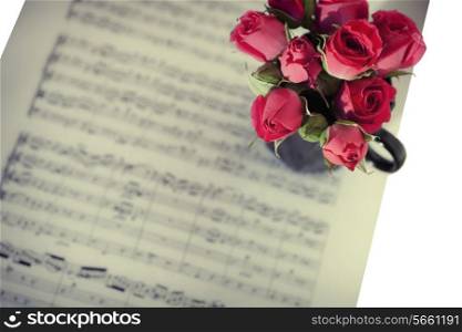 Pink roses on sheets of musical notes close up