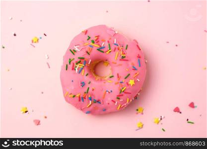 pink round donut with colored sprinkles on a pastel background, top view