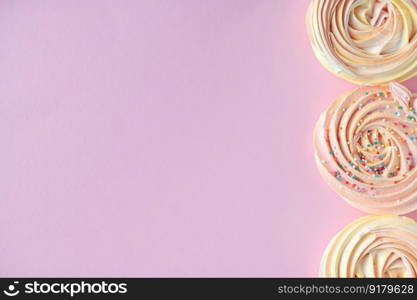 Pink round sweet meringues lie on a pink background. Pink round sweet meringues lie on a pink background on the side