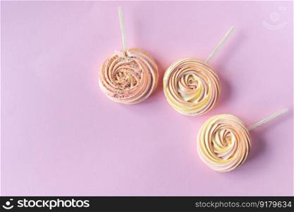 Pink round sweet meringues lie on a pink background. Pink round sweet meringues on a stick with decor lie on a pink background