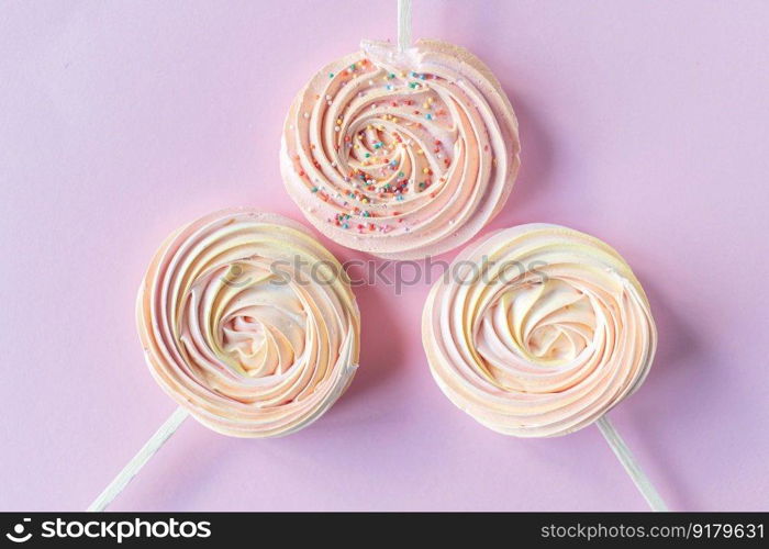 Pink round sweet meringues on a stick lie on a pink background. Colorful bright round sweet meringues on the shelf lie on a pink background