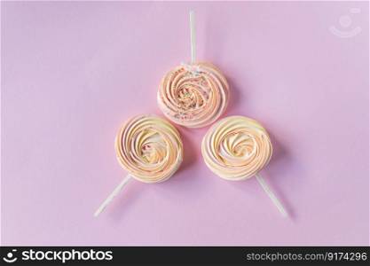 Pink round sweet meringues on a stick with decor lie on aπnk background. Pink round sweet meringues with decor lie on aπnk background