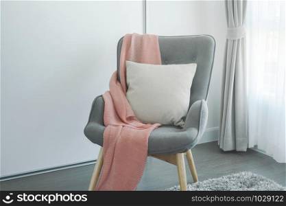 Pink scarf and beige pillow on gray armchair at the corner of living room