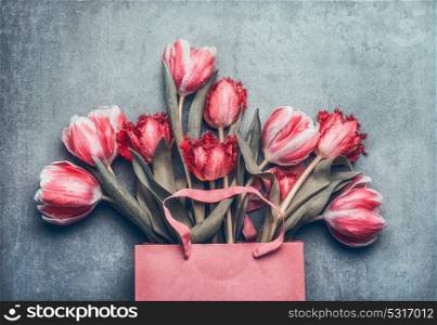 Pink shopping bag with beautiful tulips bunch, top view