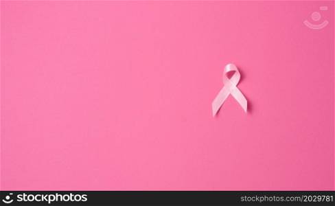 pink silk ribbon in the form of a loop on a pink background. Symbol of the fight against breast cancer