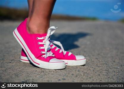 Pink sneakers on girl, young woman legs, outdoors