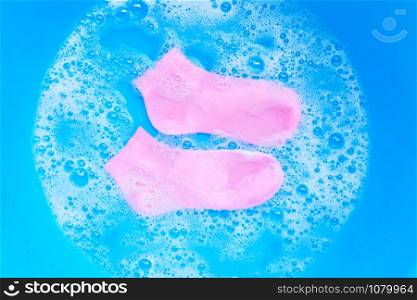Pink socks soaking in powder detergent water dissolution. Laundry concept.