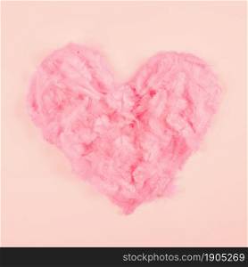 pink soft feather heart shape peach colored background. Beautiful photo. pink soft feather heart shape peach colored background