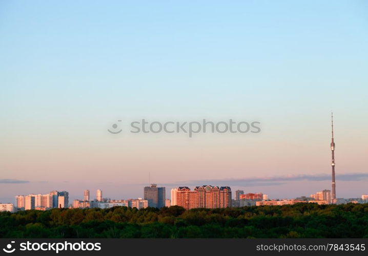 pink sunset in blue sky over urban houses and TV tower in spring