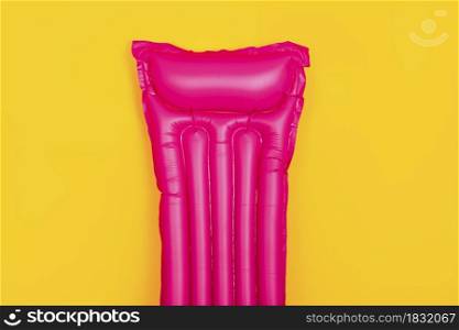 pink swim mattress on a yellow background, concept of summer vacation at sea