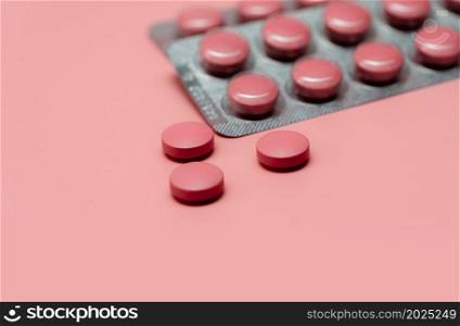 Pink tablets pill on blur blister pack of tablets pills on pink background. Prescription drugs. Woman health concept. Pharmaceutical industry. Online pharmacy banner. Drugs packaging. Treatment dose.