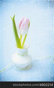 Pink tulip in vase with ribbon on blue textured background, romantic vintage card