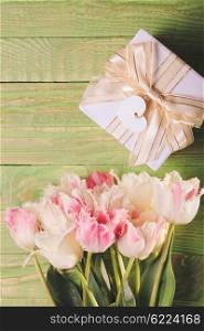 Pink tulips and gift box on a green wooden table. Tulips and gift box