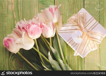 Pink tulips and gift box on a green wooden table. Tulips and gift box