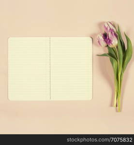 Pink tulips and notebook on pink background. Flat lay. Overhead view.