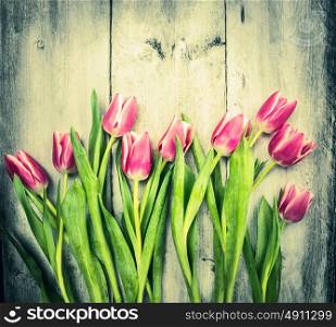 Pink tulips on old wooden background, toning