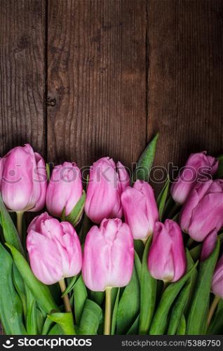 Pink tulips over old wooden table as a background