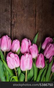 Pink tulips over old wooden table as a background