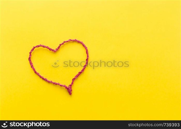 Pink wire heart shaped on yellow background. Love concept. Pink wire heart shaped on yellow background