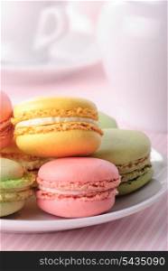 Pink, yellow, green macaroones on white plate close up