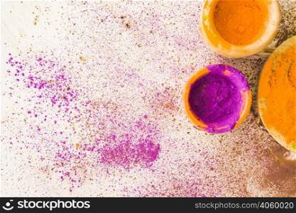 pink yellow holi powder bowl with stained white background