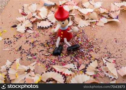 Pinocchio doll sitting amid pencil shavings
