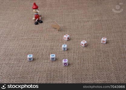 Pinocchio doll sitting on canvas beside letter cubes