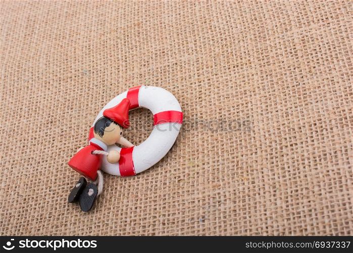 Pinocchio doll tied to a life preserver on canvas