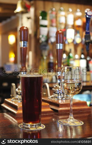 pint of beer and glass of white wine on bar in a pub