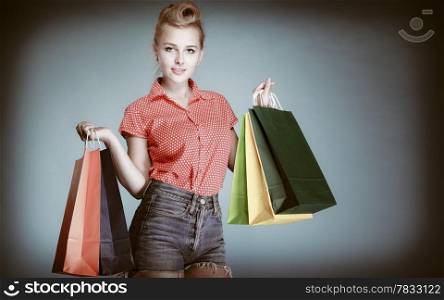 Pinup girl young woman in retro style buying clothes. Client holding shopping bags on gray. Retail and sale. Studio shot.