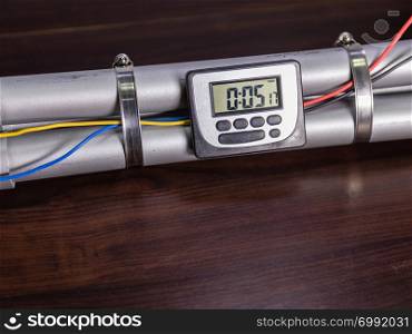 Pipe bomb with an lcd clock timer to trigger detonation, on wooden table