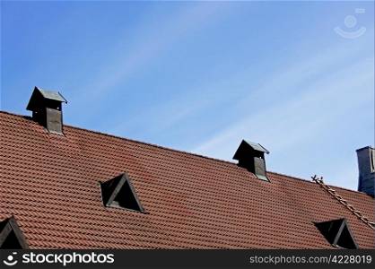 Pipe of ventilation and windows on a roof of tiles