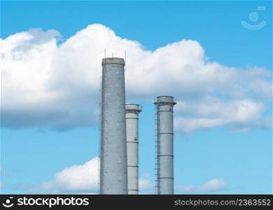Pipes of an industrial enterprise against a blue sky with clouds. Chimney without smoke. industrial pipes on sky background