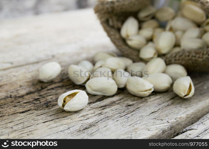 Pistachio nuts in sackcloth bag on wooden background